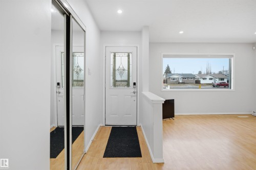 The entryway features a white door with decorative glass inserts, recessed lighting, and light wood flooring - 16049 95 Avenue, Edmonton, AB - Indoor Photo Showing Other Room