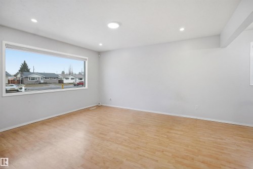 This room features light-toned hardwood flooring, recessed lighting, and a large window providing views of the neighborhood - 16049 95 Avenue, Edmonton, AB - Indoor Photo Showing Other Room