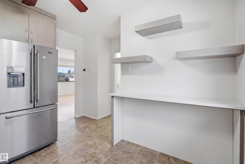 The kitchen features a stainless steel refrigerator, light-toned cabinetry, and tiled flooring - 16049 95 Avenue, Edmonton, AB - Indoor Photo Showing Kitchen