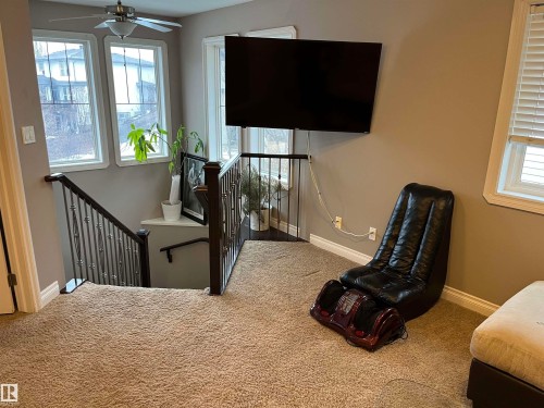 The property features a staircase with wrought iron railings, an overhead ceiling fan, and large windows providing ample natural light - 21917 95A Avenue, Edmonton, AB - Indoor