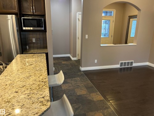 The property features a kitchen with stainless steel appliances and dark wood cabinetry, and a granite countertop - 21917 95A Avenue, Edmonton, AB - Indoor