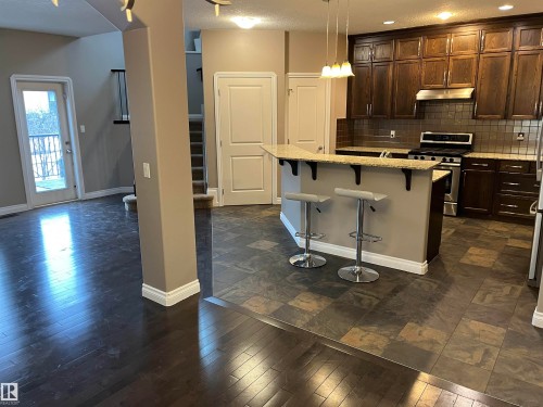 The property features a kitchen with dark wood cabinetry, stainless steel appliances, and a tiled backsplash - 21917 95A Avenue, Edmonton, AB - Indoor Photo Showing Kitchen With Upgraded Kitchen