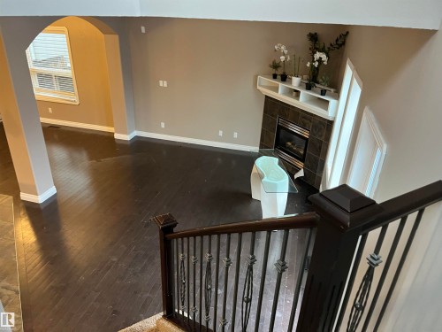 Living area featuring dark hardwood floors, a fireplace with dark tile surround, and a white mantel with integrated shelving - 21917 95A Avenue, Edmonton, AB - Indoor Photo Showing Other Room With Fireplace