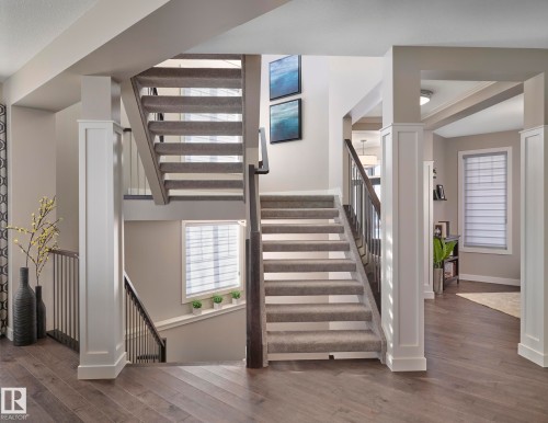 Interior featuring hardwood floors, a carpeted staircase with dark wood handrails, and white trim columns - 1003 Huckell Place, Edmonton, AB - Indoor Photo Showing Other Room