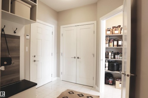 Entrance foyer with light-colored tile flooring, a built-in storage bench, and white doors - 1003 Huckell Place, Edmonton, AB - Indoor Photo Showing Other Room