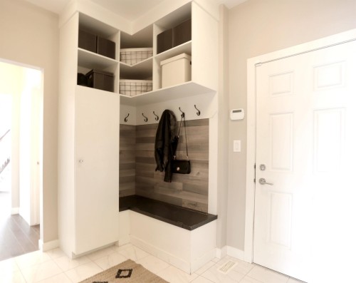 Entryway featuring tiled flooring, a built-in bench with hooks, overhead shelving, and a paneled white door - 1003 Huckell Place, Edmonton, AB - Indoor Photo Showing Other Room