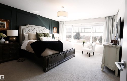 Inviting sleeping area featuring a dark accent wall, light-colored carpeting, and a large window with a scenic view - 1003 Huckell Place, Edmonton, AB - Indoor Photo Showing Bedroom