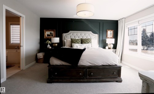 This bedroom features carpeted flooring, a dark accent wall, and a large window providing views of the outdoors - 1003 Huckell Place, Edmonton, AB - Indoor Photo Showing Bedroom