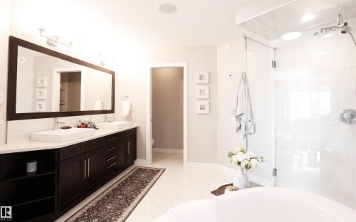 Bathroom featuring a large vanity with two rectangular vessel sinks, a spacious glass-enclosed shower, and light-colored tile flooring - 1003 Huckell Place, Edmonton, AB - Indoor Photo Showing Bathroom
