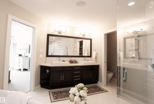 The bathroom features a double vanity with two vessel sinks, a large mirror, and a glass-enclosed shower - 1003 Huckell Place, Edmonton, AB - Indoor Photo Showing Bathroom
