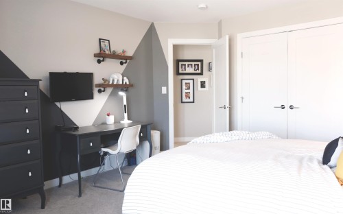 This room features a neutral color palette with accent walls, carpeted floors, and white double closet doors - 1003 Huckell Place, Edmonton, AB - Indoor Photo Showing Bedroom