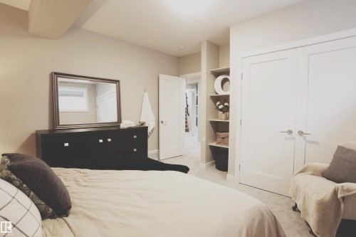 This inviting room features neutral-toned walls, plush carpeting, and built-in shelving, providing practical storage and display space - 1003 Huckell Place, Edmonton, AB - Indoor Photo Showing Bedroom