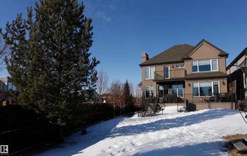 The property features a brown stucco exterior with a multi-level deck and balcony, offering ample outdoor living space - 1003 Huckell Place, Edmonton, AB - Outdoor With Balcony
