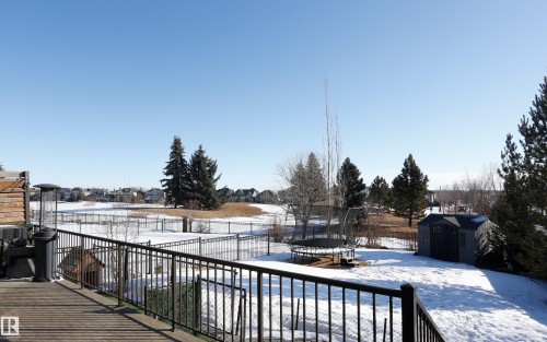 The property features a spacious deck with a metal railing, overlooking a yard with a shed and mature trees - 1003 Huckell Place, Edmonton, AB - Outdoor With Balcony