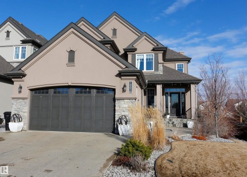 The property features a stucco exterior with stone accents, a multi-pane garage door, and a covered front entry with stone steps - 1003 Huckell Place, Edmonton, AB - Outdoor