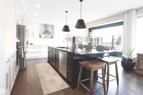 The kitchen features white cabinetry, a dark island with a granite countertop, and stainless steel appliances - 1003 Huckell Place, Edmonton, AB - Indoor Photo Showing Kitchen With Upgraded Kitchen