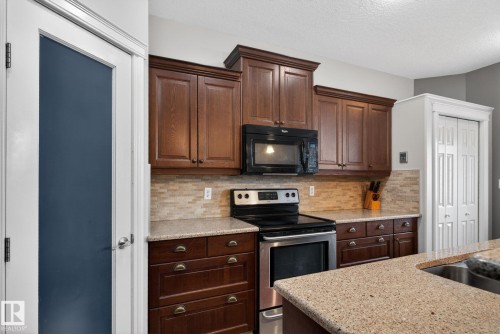 Kitchen featuring wooden cabinetry, a tiled backsplash, and light-colored countertops - 10418 69 Avenue, Edmonton, AB - Indoor Photo Showing Kitchen With Double Sink