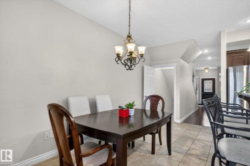 Dining area featuring a chandelier, tile flooring, and a view into the entryway with a dark wood door - 10418 69 Avenue, Edmonton, AB - Indoor Photo Showing Dining Room