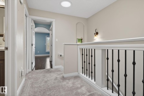 A well-lit landing area featuring soft gray carpeting, white trim, and a white railing with black balusters - 10418 69 Avenue, Edmonton, AB - Indoor Photo Showing Other Room