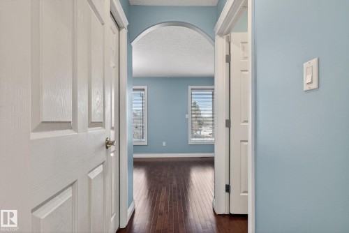 Hallway featuring light blue walls, hardwood flooring, and an arched doorway - 10418 69 Avenue, Edmonton, AB - Indoor Photo Showing Other Room
