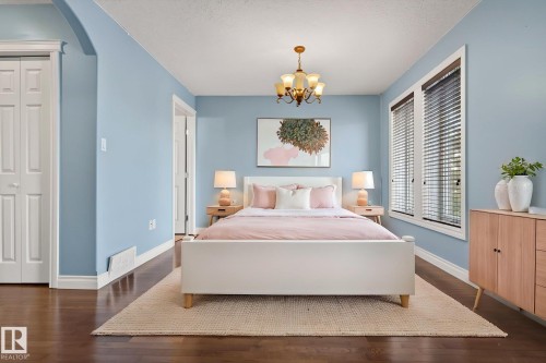 This room features hardwood floors, a prominent chandelier, and large windows with blinds - 10418 69 Avenue, Edmonton, AB - Indoor Photo Showing Bedroom