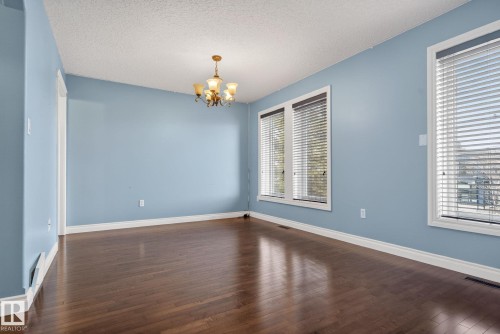 This room features rich hardwood flooring, light blue walls, and a white trim throughout - 10418 69 Avenue, Edmonton, AB - Indoor Photo Showing Other Room