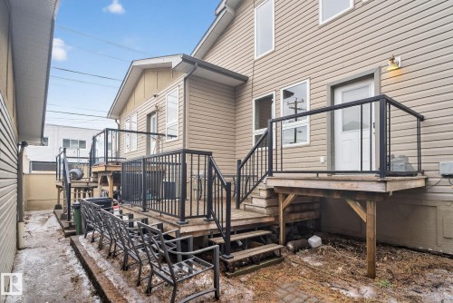The property features a tiered deck with black railings and light wood steps, offering direct access to the exterior - 10418 69 Avenue, Edmonton, AB - Outdoor With Exterior