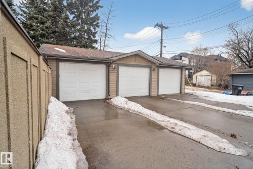 The property features a three-car garage with individual white garage doors and exterior lighting fixtures - 10418 69 Avenue, Edmonton, AB - Outdoor