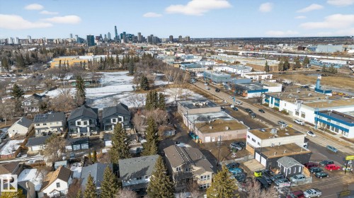 Aerial view showcasing the property's surroundings, including other residential properties, commercial buildings, and a distant city skyline - 10418 69 Avenue, Edmonton, AB - Outdoor With View