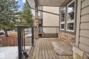 The property features a wooden deck with glass railing, stone accent pillars, and a stone facade - 10418 69 Avenue, Edmonton, AB  - Outdoor With Exterior 