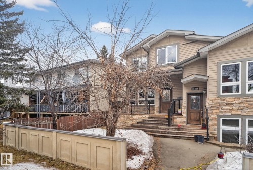 The property features a stone and siding exterior, multiple windows, and a wood fence - 10418 69 Avenue, Edmonton, AB - Outdoor
