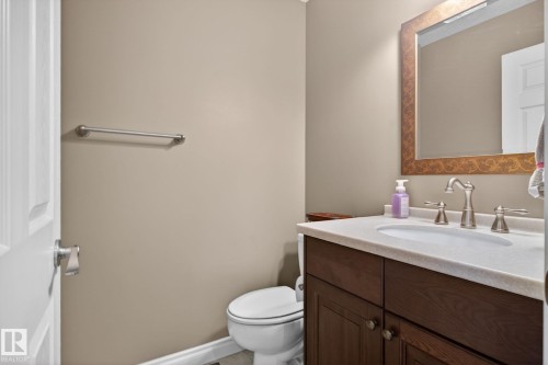 This bathroom features a dark wood vanity with a light-colored countertop and a mirror with an ornate frame - 10418 69 Avenue, Edmonton, AB - Indoor Photo Showing Bathroom