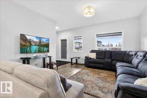 The living area features light-colored walls, recessed lighting, and windows that provide natural illumination - 203 Cavanagh Common, Edmonton, AB - Indoor Photo Showing Living Room