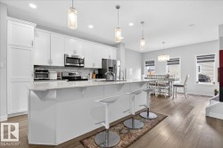 The kitchen features white cabinetry, stainless steel appliances, and a central island with a light-colored countertop - 