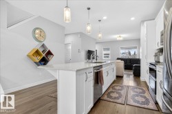 The kitchen features an island with white cabinetry, a sink with a gooseneck faucet, and pendant lighting overhead - 