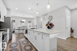 The kitchen features white cabinetry, stainless steel appliances, and a central island with a light-colored countertop - 