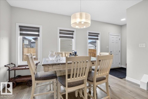 The dining area features light-toned flooring, white walls, and a modern drum pendant light fixture - 203 Cavanagh Common, Edmonton, AB - Indoor Photo Showing Dining Room