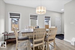 The dining area features light-toned flooring, white walls, and a modern drum pendant light fixture - 