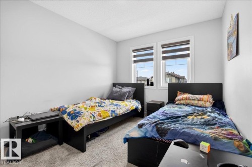 This room features light gray walls, two windows with blinds, and carpeted floors - 203 Cavanagh Common, Edmonton, AB - Indoor Photo Showing Bedroom