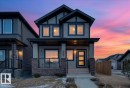 The property features a two-story exterior with light-colored siding, dark trim, and a prominent front entrance - 203 Cavanagh Common, Edmonton, AB  - Outdoor With Facade 