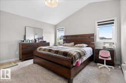 This bedroom features a vaulted ceiling, neutral wall color, and carpeted flooring - 