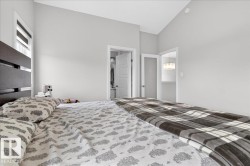 This bedroom features light gray walls, a window with blinds, and a dark-colored bed frame - 