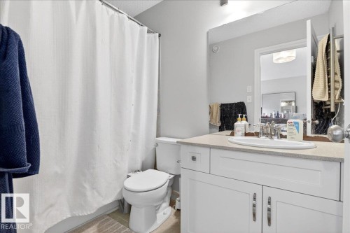 Bathroom featuring a white vanity with a rectangular sink, a large mirror, and a toilet - 203 Cavanagh Common, Edmonton, AB - Indoor Photo Showing Bathroom