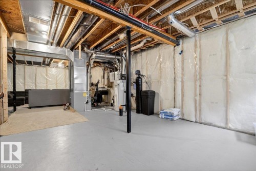 The unfinished basement features exposed wooden ceiling joists, ductwork, and structural beams, offering potential for future customization - 203 Cavanagh Common, Edmonton, AB - Indoor Photo Showing Basement