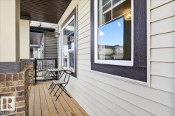 The property features a balcony with wood decking, brick accents, and light-colored siding - 