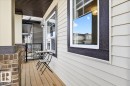 The property features a balcony with wood decking, brick accents, and light-colored siding - 203 Cavanagh Common, Edmonton, AB  - Outdoor With Deck Patio Veranda With Exterior 