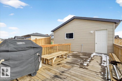 The property features a spacious wooden deck with a wooden railing and a detached structure with siding and a single window - 203 Cavanagh Common, Edmonton, AB - Outdoor With Deck Patio Veranda With Exterior
