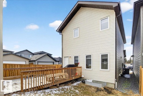 The property features an exterior with light-colored siding, a dark-colored roof, and a wooden deck with railing - 203 Cavanagh Common, Edmonton, AB - Outdoor With Exterior