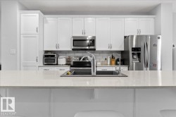 Kitchen featuring white cabinetry, a stainless steel refrigerator, and a double basin sink with a chrome faucet - 