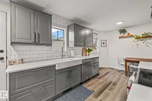 The kitchen features modern gray cabinetry, white countertops, and a white subway tile backsplash - 9321 92 Street, Edmonton, AB - Indoor